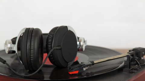 Ακουστικά ακουμπισμένα σε δίσκο βινυλίου σε πικ-απ